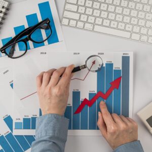 Additional Services top view office desk with growth chart hands holding magnifying glass